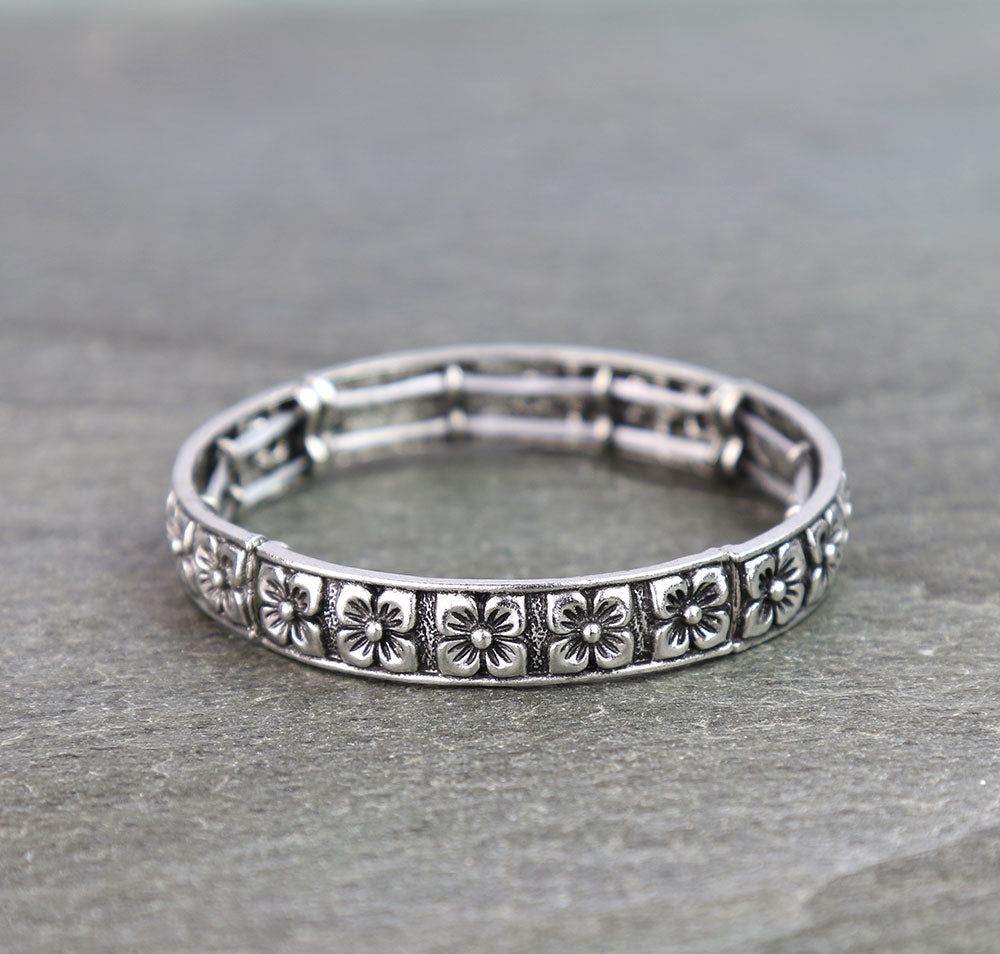 Silver bracelet with floral patterns on a gray background