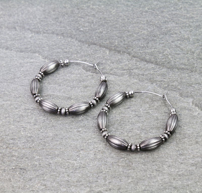 Pair of beaded hoop earrings on a gray background