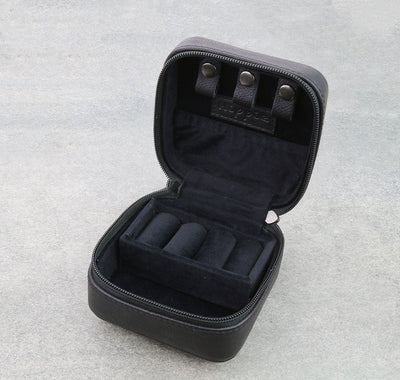 Black jewelry case with three compartments on a light gray background