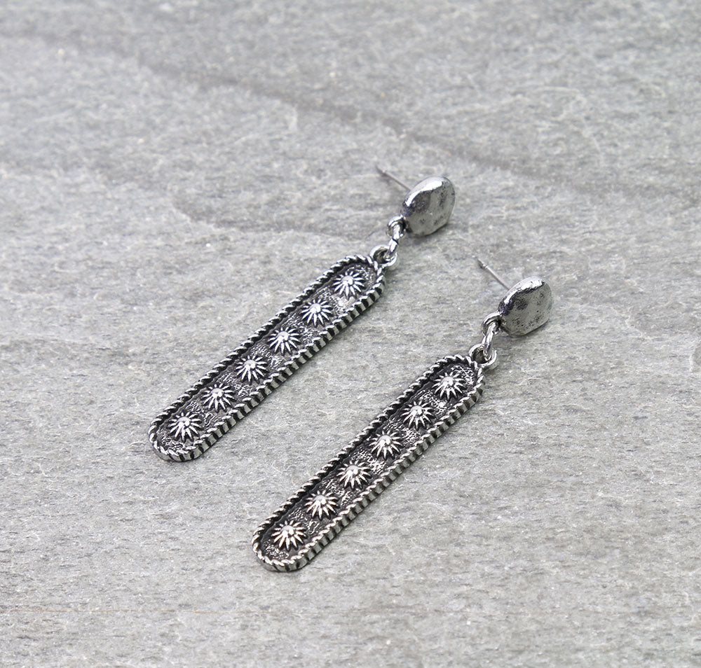 Pair of silver earrings on a textured gray surface