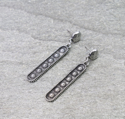 Pair of silver earrings on a textured gray surface