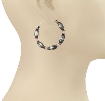 Hoop earrings with black and pink beads on a mannequin.