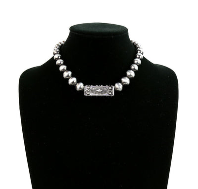 Silver beaded necklace with a rectangular clasp on a black mannequin bust.