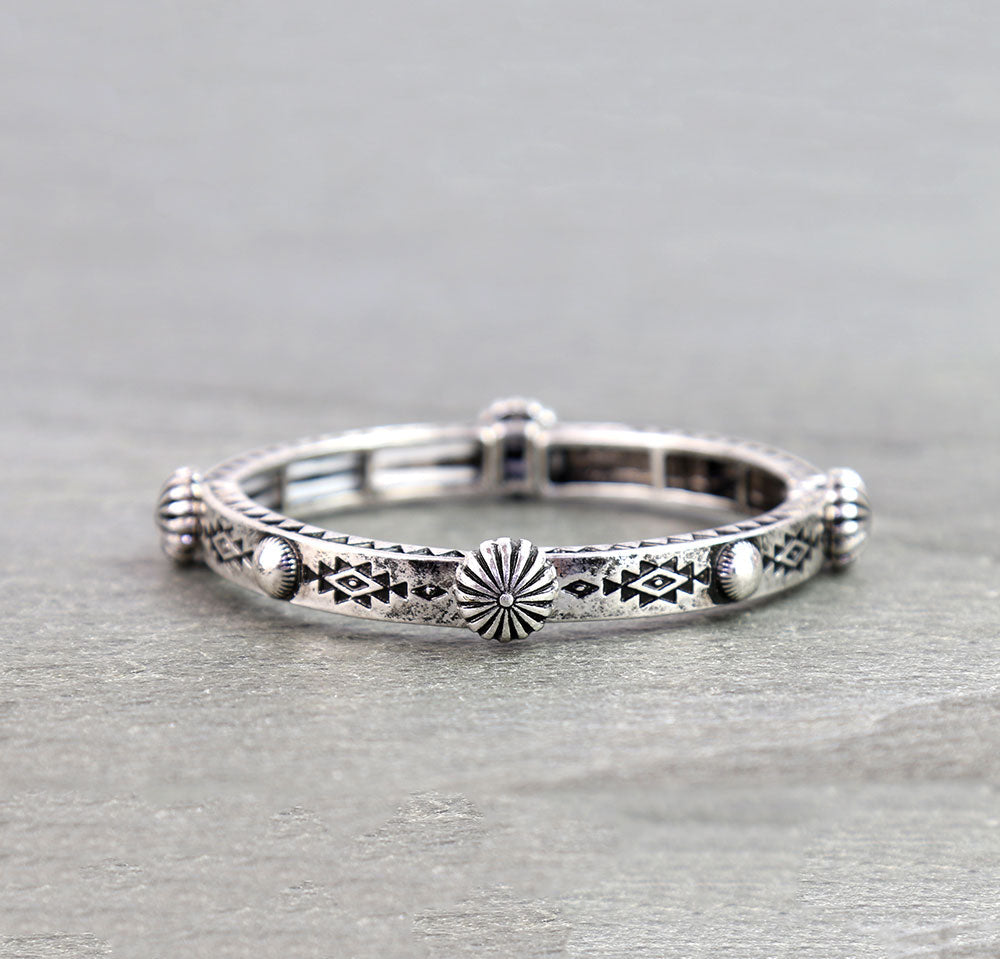 Silver ring with intricate designs on a gray surface