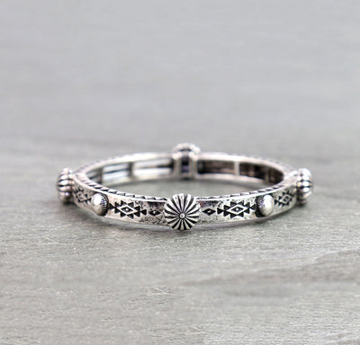 Silver ring with intricate designs on a gray surface