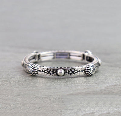 Silver bracelet with tribal patterns on a gray surface