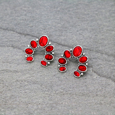 Silver earrings with red stones on a gray surface