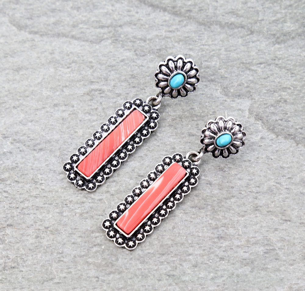 Pair of earrings with coral and turquoise stones on a gray background