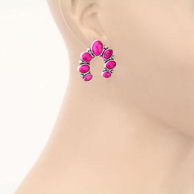Pink gemstone earrings on a mannequin ear