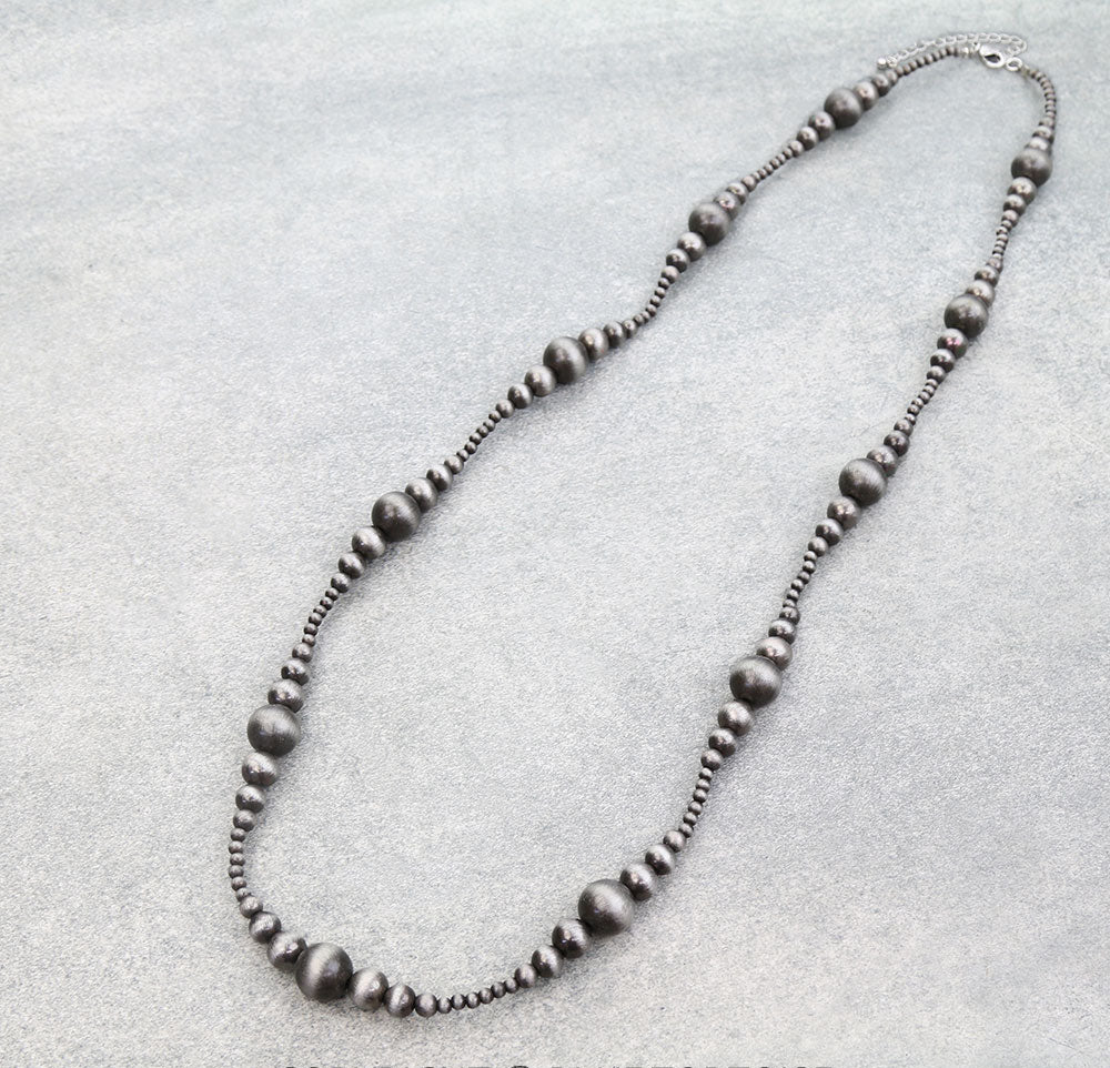 Silver beaded necklace on a light gray background