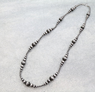 Silver beaded necklace on a light gray background