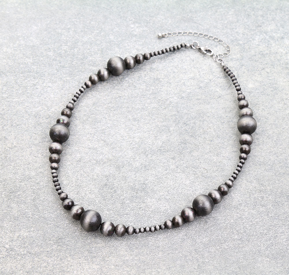 Necklace with dark beads on a light gray background