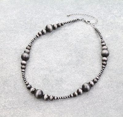 Necklace with dark beads on a light gray background