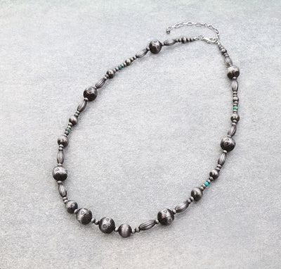 Stamped silver bead necklace on a light background