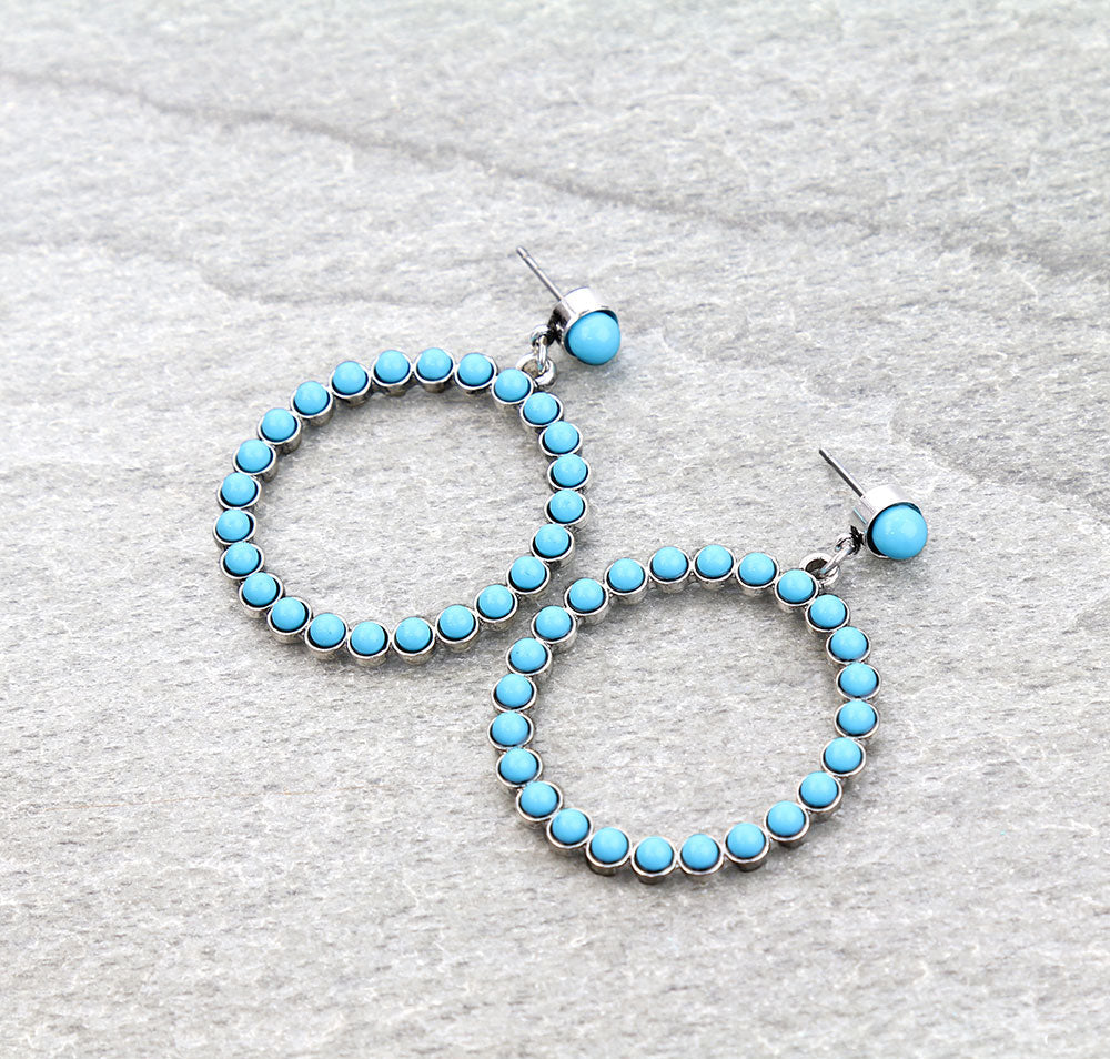 Turquoise hoop earrings on a gray textured background