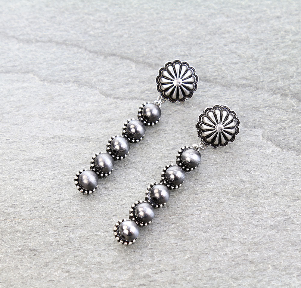 Silver earrings with floral tops on a light gray background
