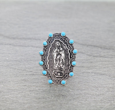 silver & turquoise lady of Guadalupe ring on a gray surface