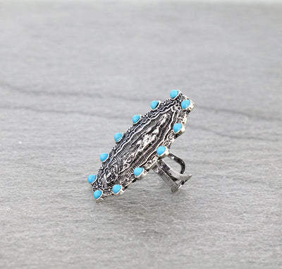 silver & turquoise lady of Guadalupe ring on a gray surface