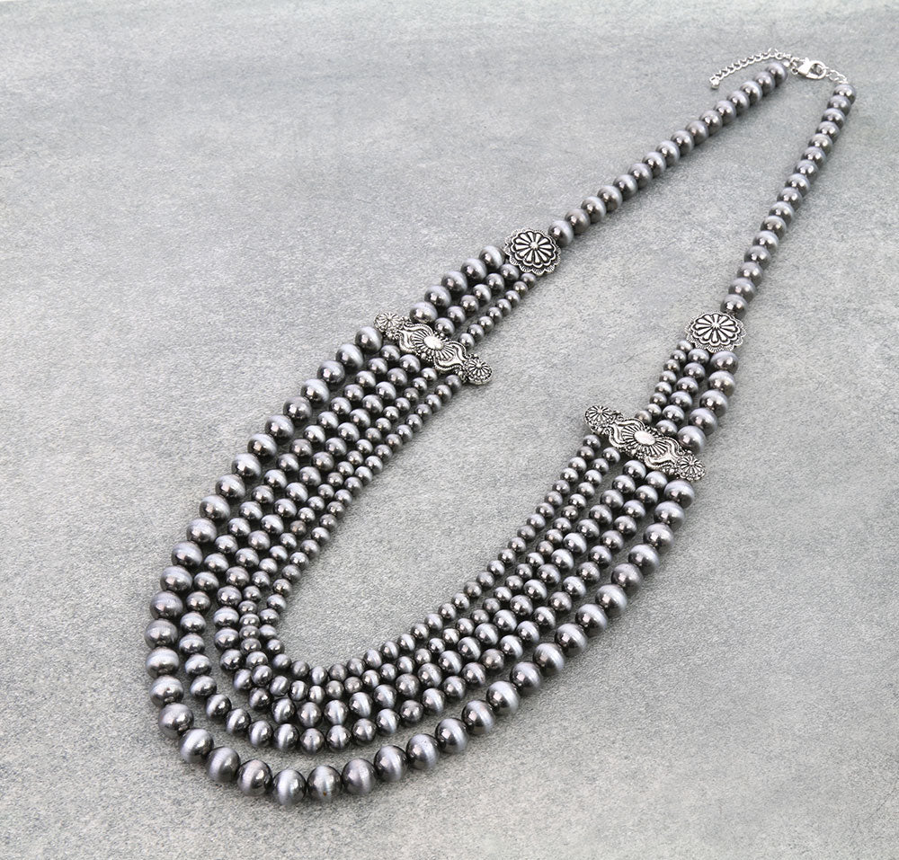 Silver beaded necklace with decorative elements on a gray background