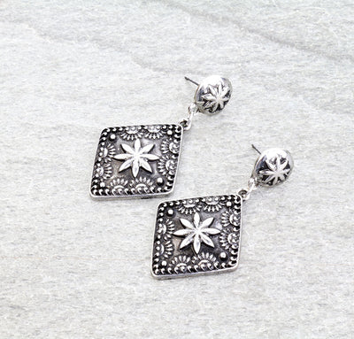 pair of silver concho earrings on a gray background