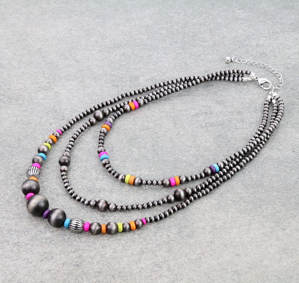 Necklace with silver beads and colorful accents on a gray surface.