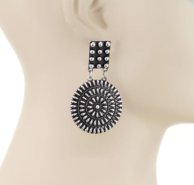 Silver circular earring on a mannequin ear.