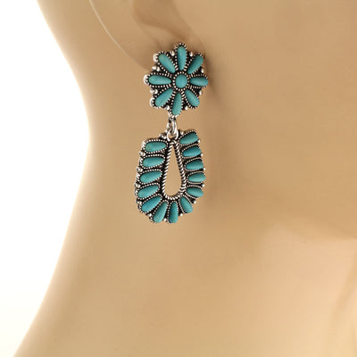 Turquoise floral earrings on a mannequin ear