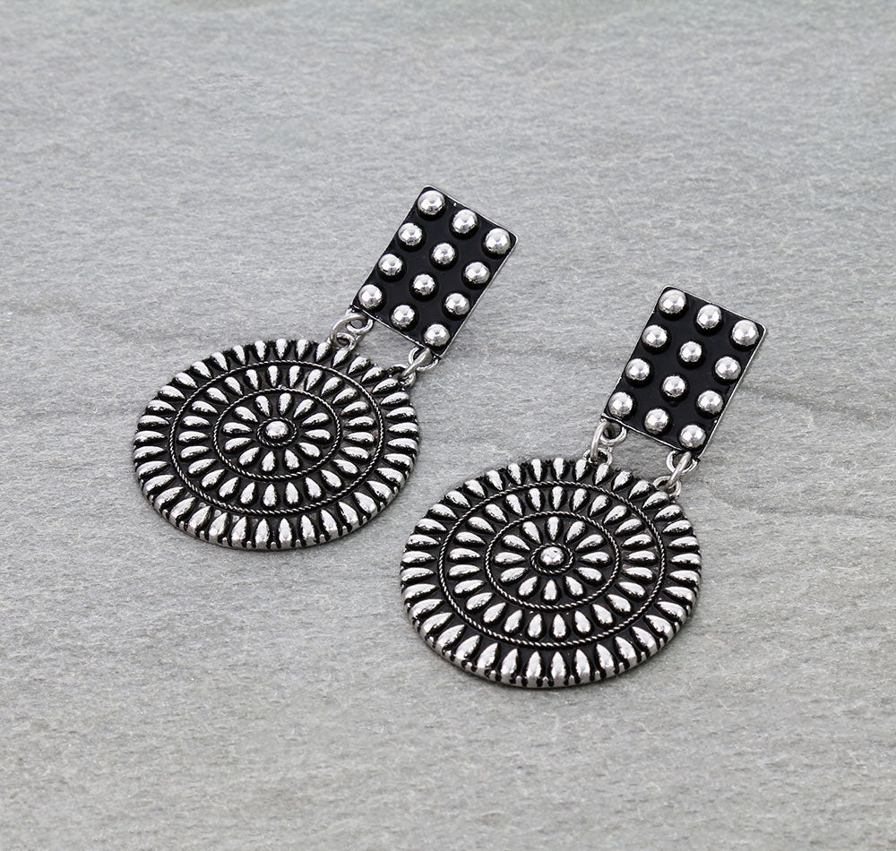 Pair of silver earrings with circular designs on a gray background