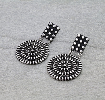 Pair of silver earrings with circular designs on a gray background