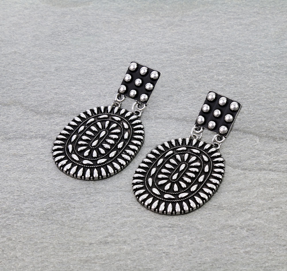 Pair of silver earrings with intricate designs on a gray background