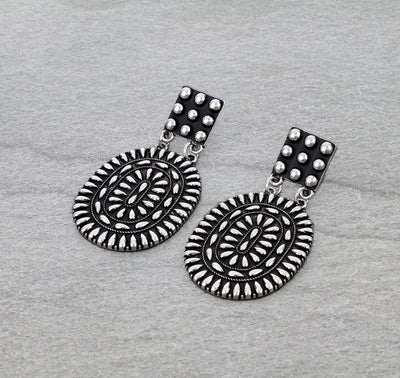 Pair of silver earrings with intricate designs on a gray background