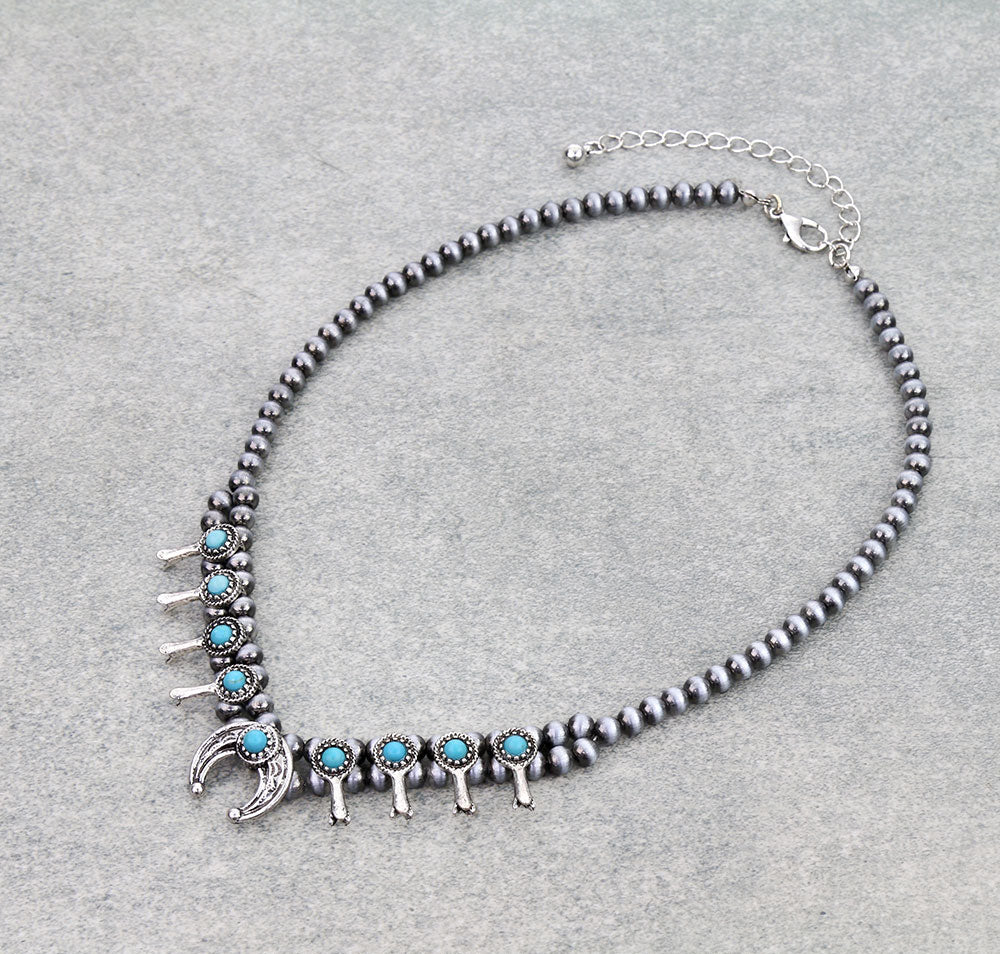 Necklace with black beads and turquoise accents on a gray background