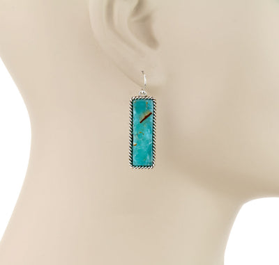 Turquoise pendant earring on a mannequin bust with 'Blue Tortoise' branding.