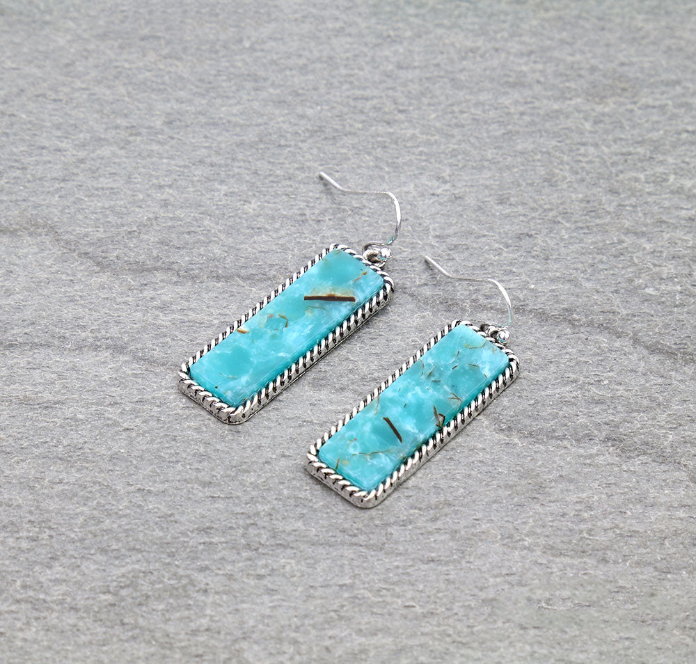 Turquoise earrings with silver frames on a gray background