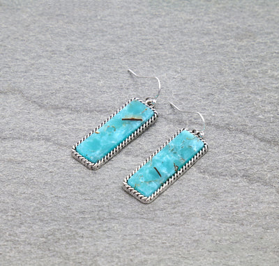 Turquoise earrings with silver frames on a gray background