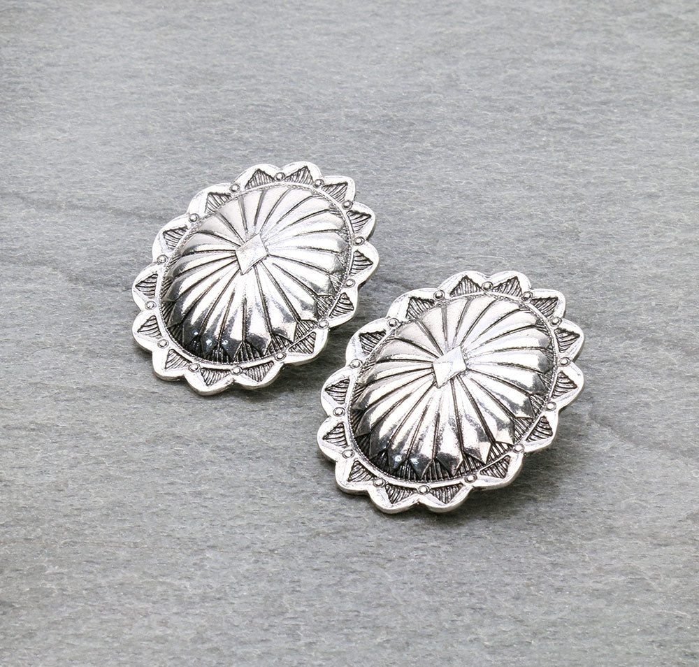 Pair of silver concho-style earrings on a gray background