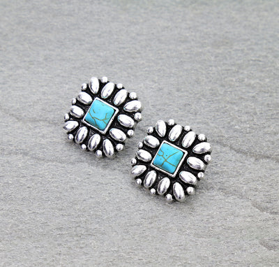 Pair of silver earrings with turquoise stones on a gray background