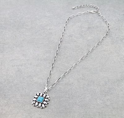 Silver necklace with a blue pendant on a gray background