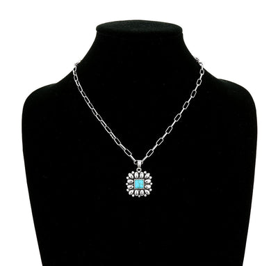 Necklace with a blue pendant on a black mannequin bust.