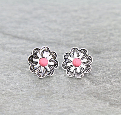 Silver flower-shaped earrings with pink centers on a gray background