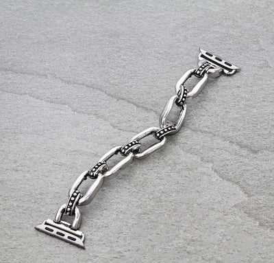 Silver chain watch band on a gray textured background