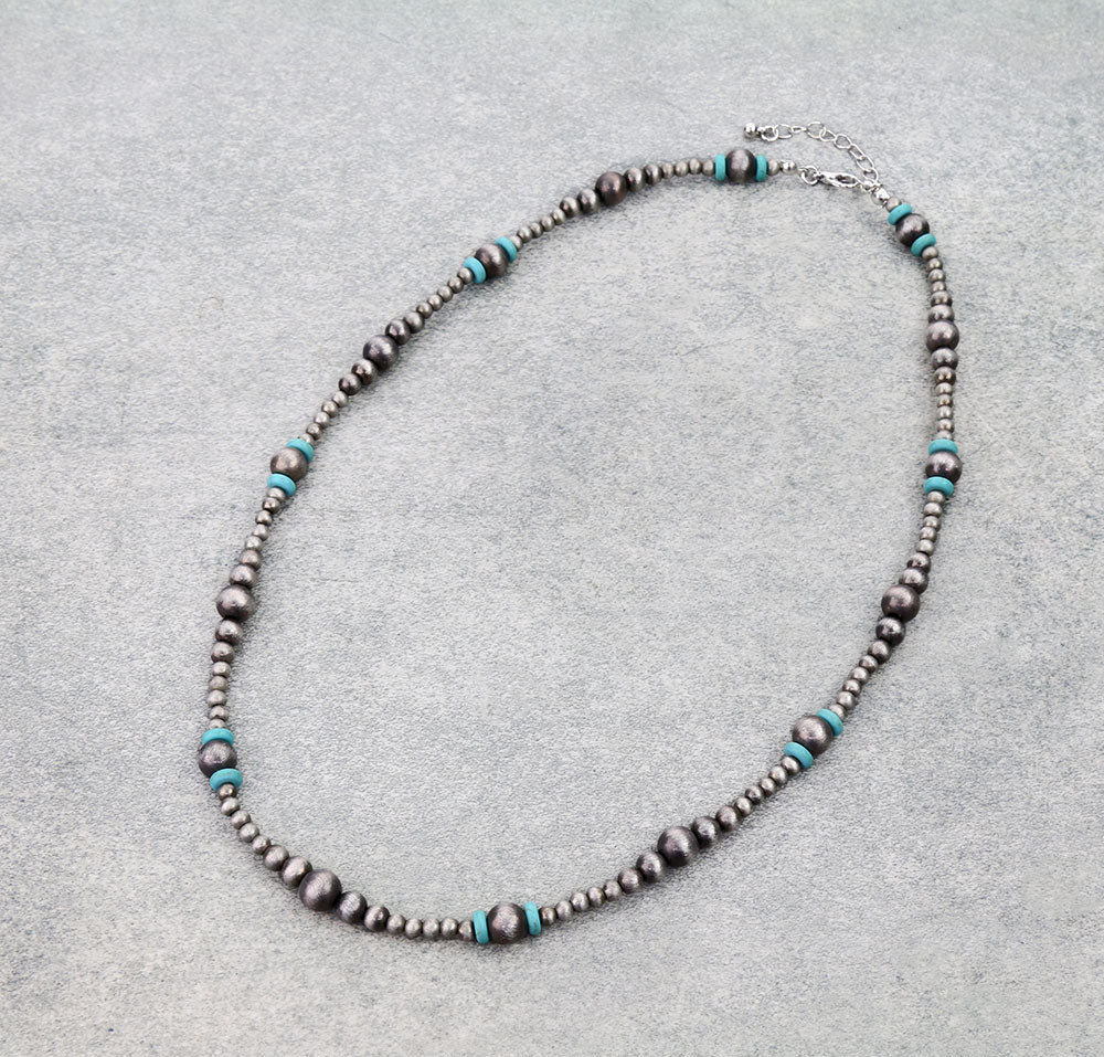 Necklace with silver and turquoise beads on a gray background