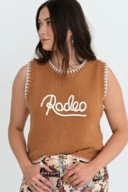 Woman wearing a brown sleeveless top with 'Rodeo' text and floral pants against a white background