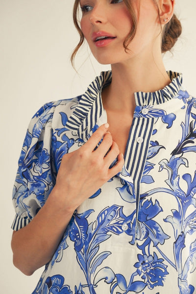 model wearing a blue & white floral dress with stripe accents on a light background