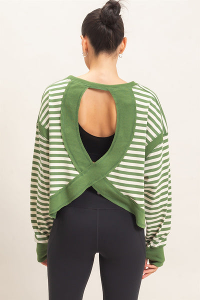 back view of model wearing a green striped sweater and black pants with a light background