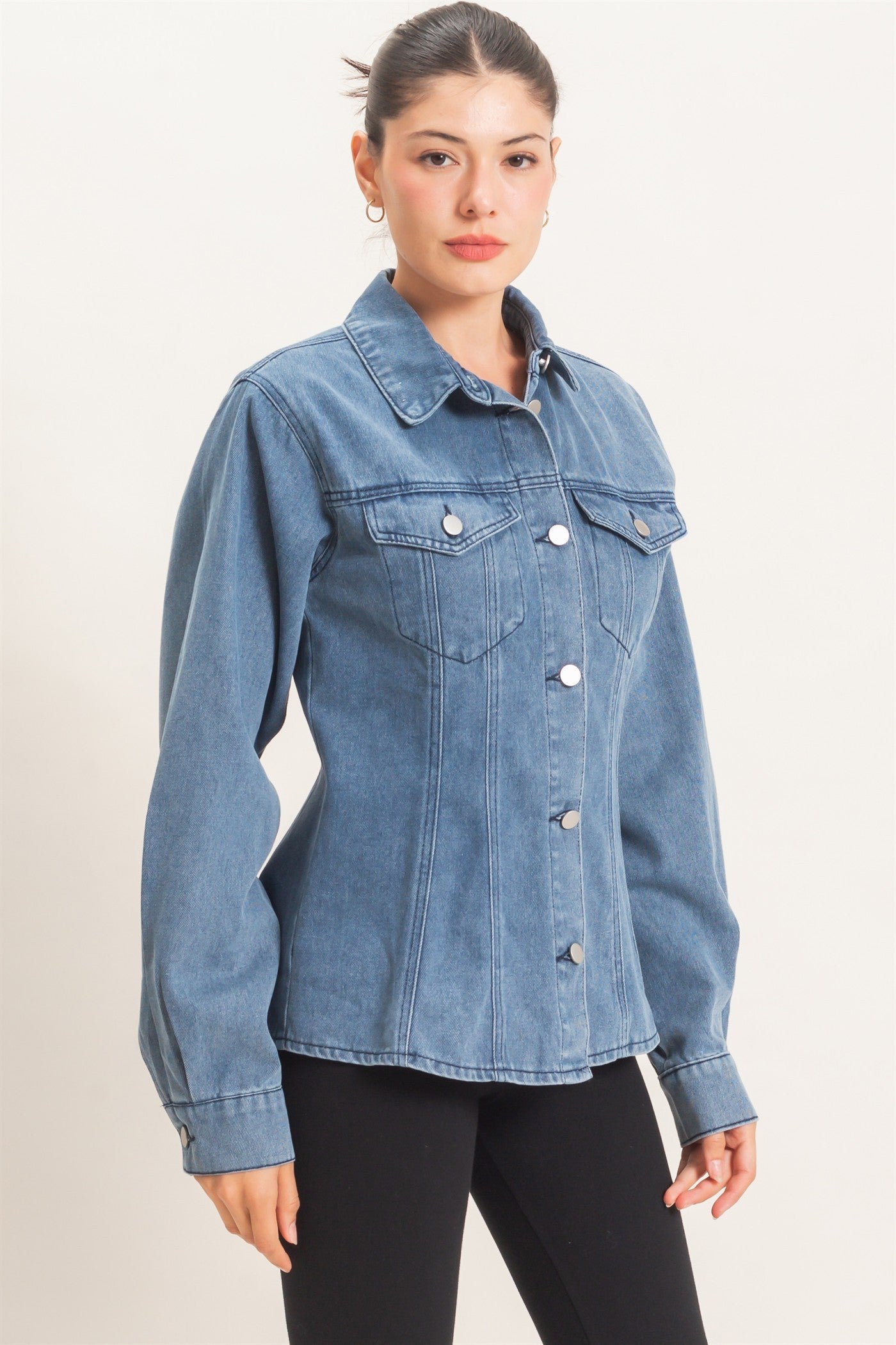 model wearing button down denim jacket and black pants with a light background