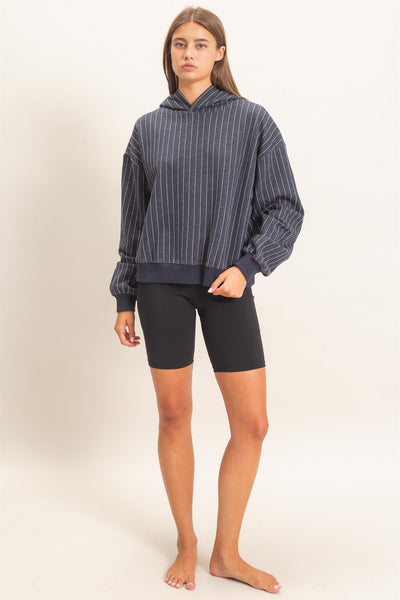 model wearing a navy striped hoodie with black shorts in front of a light background