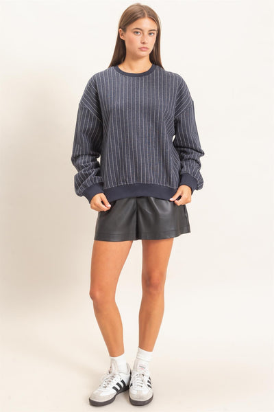model wearing navy striped sweatshirt and black shorts with a light background