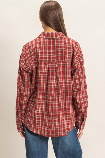 back of woman wearing a plaid shirt and jeans in front of a light background