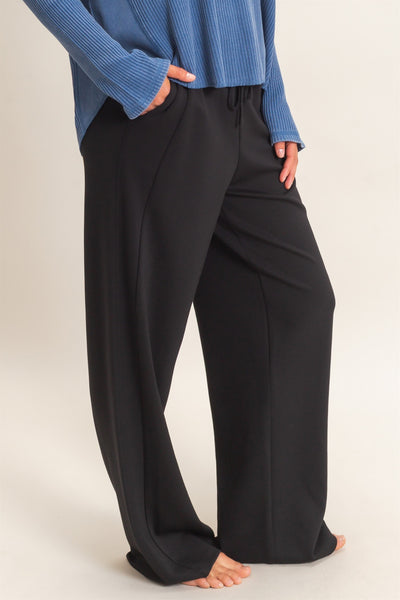 model wearing a blue shirt & black pants shown from the side with a light background